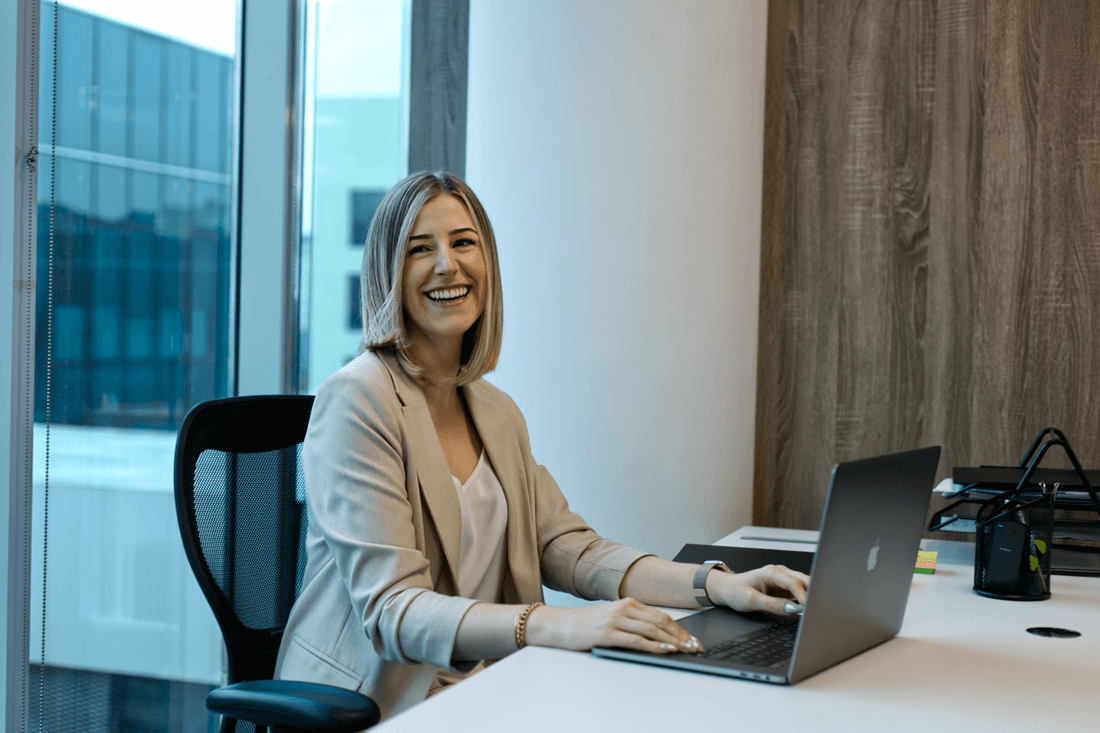 Die Lemon Spark Mitgründerin Lisa Debatin sitzt in einem Büro an einem Schreibtisch mit einem Laptop und lacht